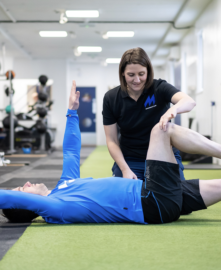 A Momentum staff member helping a client with a stretch