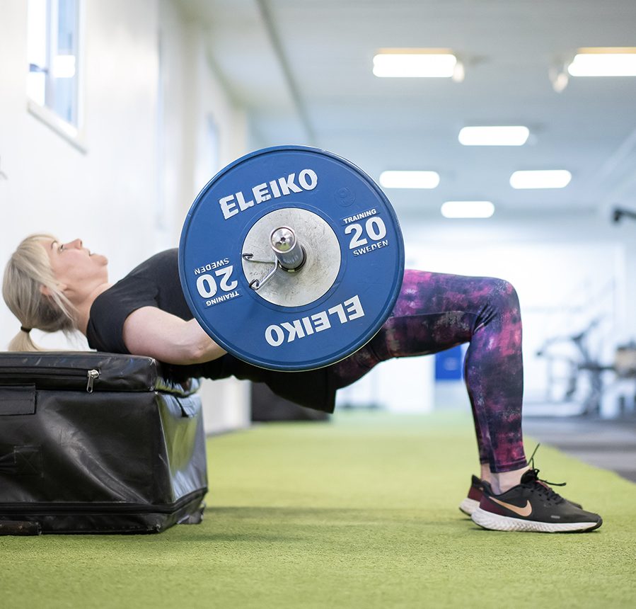 A gym user doing hip thrusts with a barbell